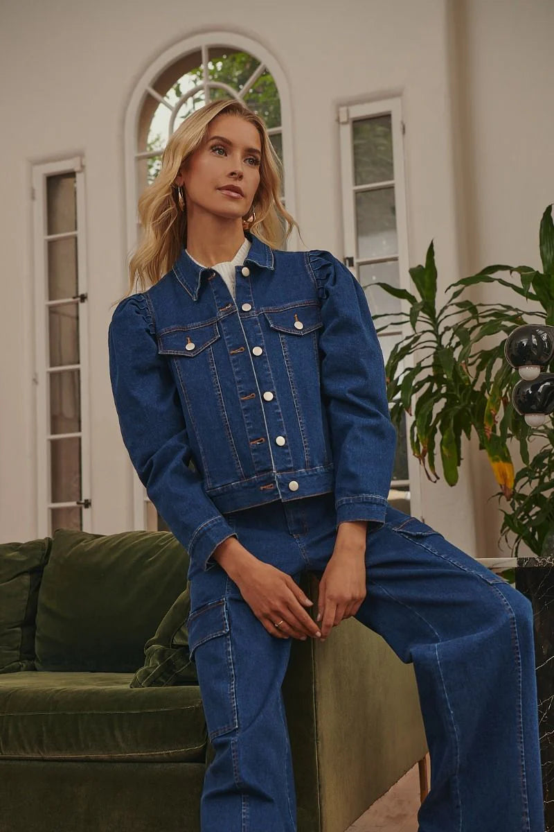 Woman wearing a blue denim outfit sitting on a green couch indoors.
